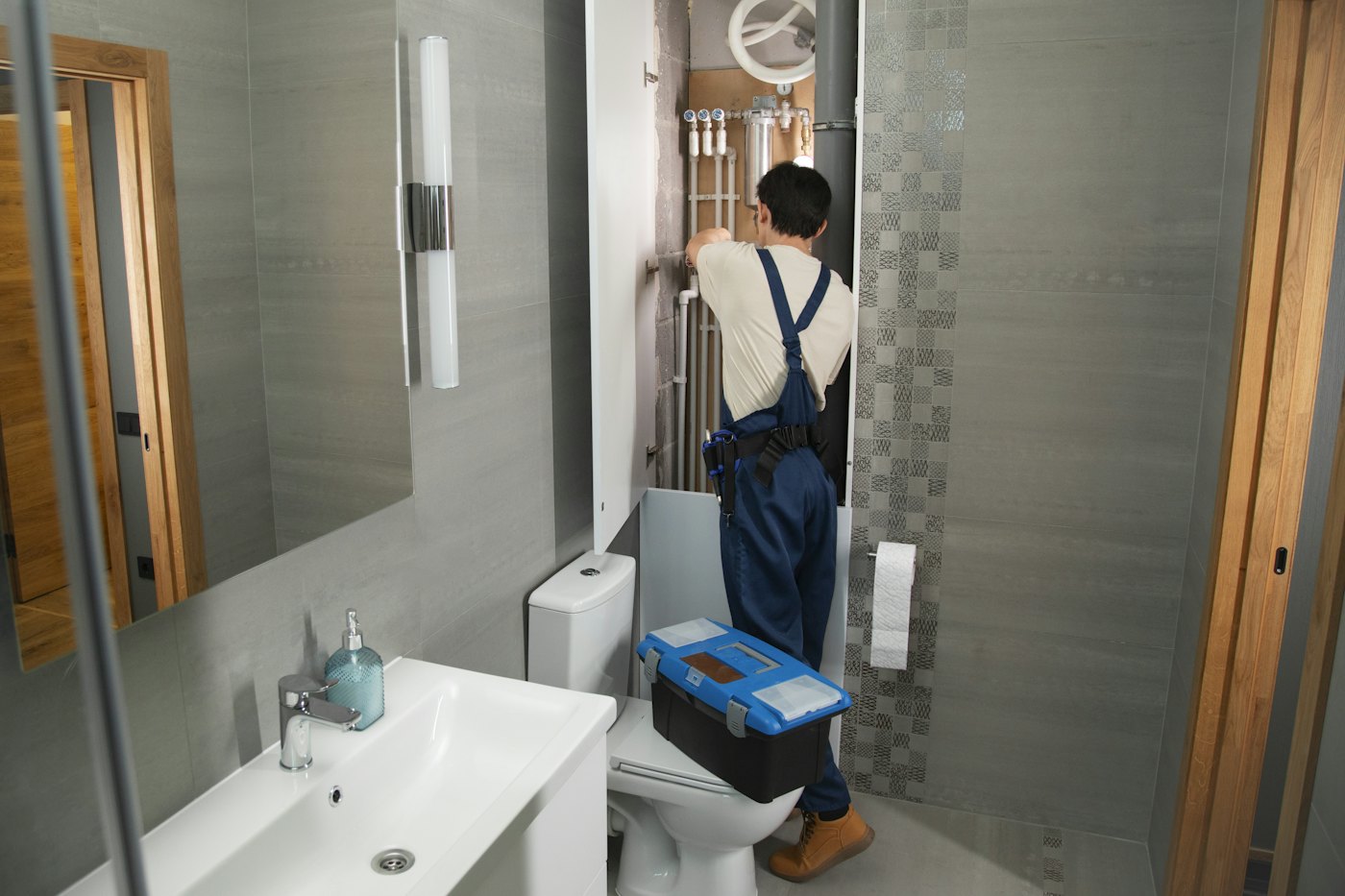 A plumber working on pipework in a bathroom